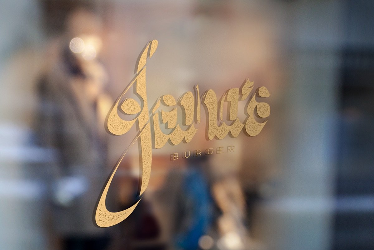 Joana’s Burger gold logo on a glass door.